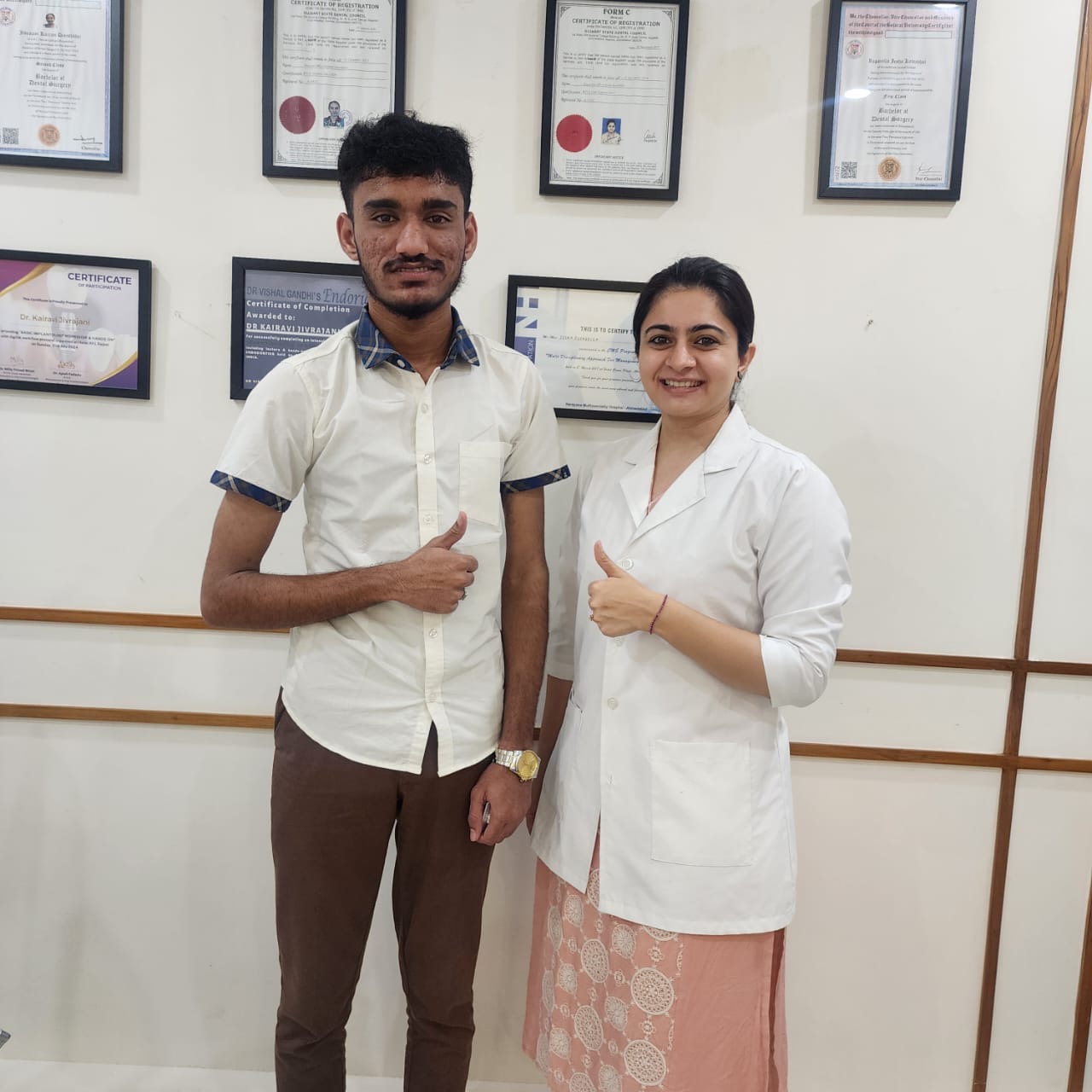 Patient with doctor in front of certificates